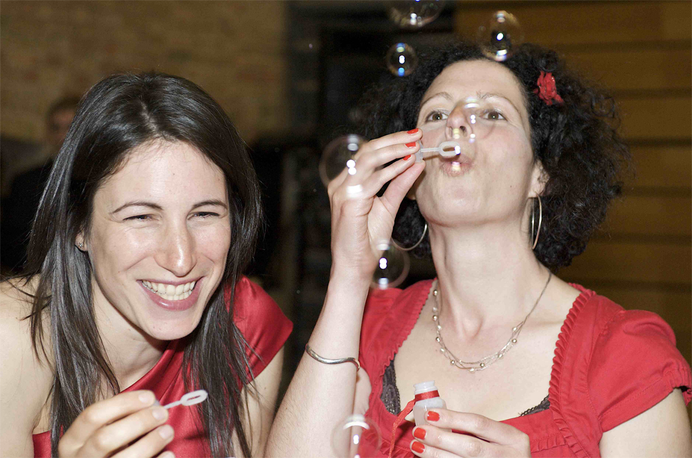 Two bridesmaids blowing bubbles at the wedding of Tammy and Nick by cambridge photographer Richard Bowring